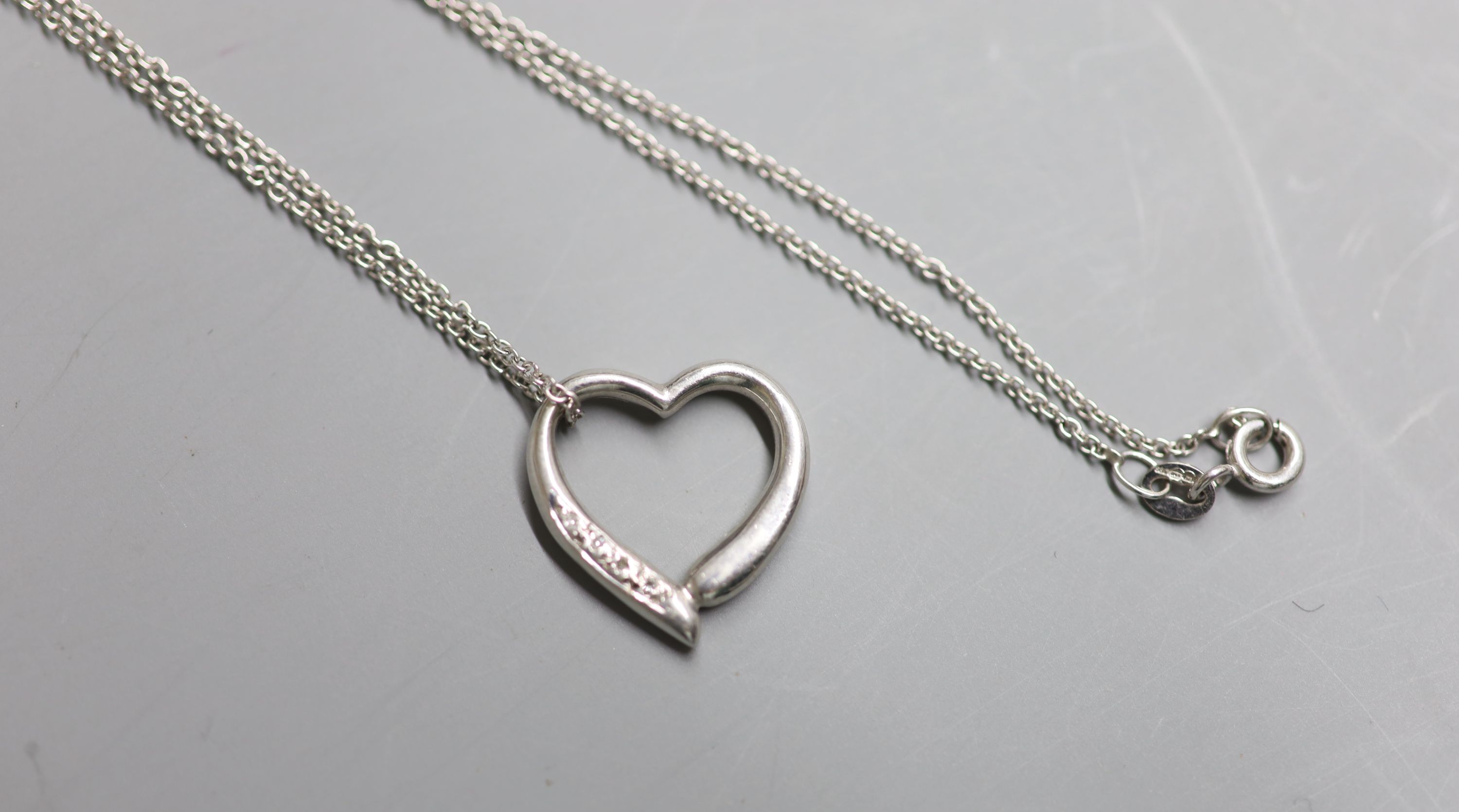 A modern 9ct white gold and diamond chip set openwork heart pendant, 18mm, on a 9ct white gold chain, 39cm, gross 3.8 grams.